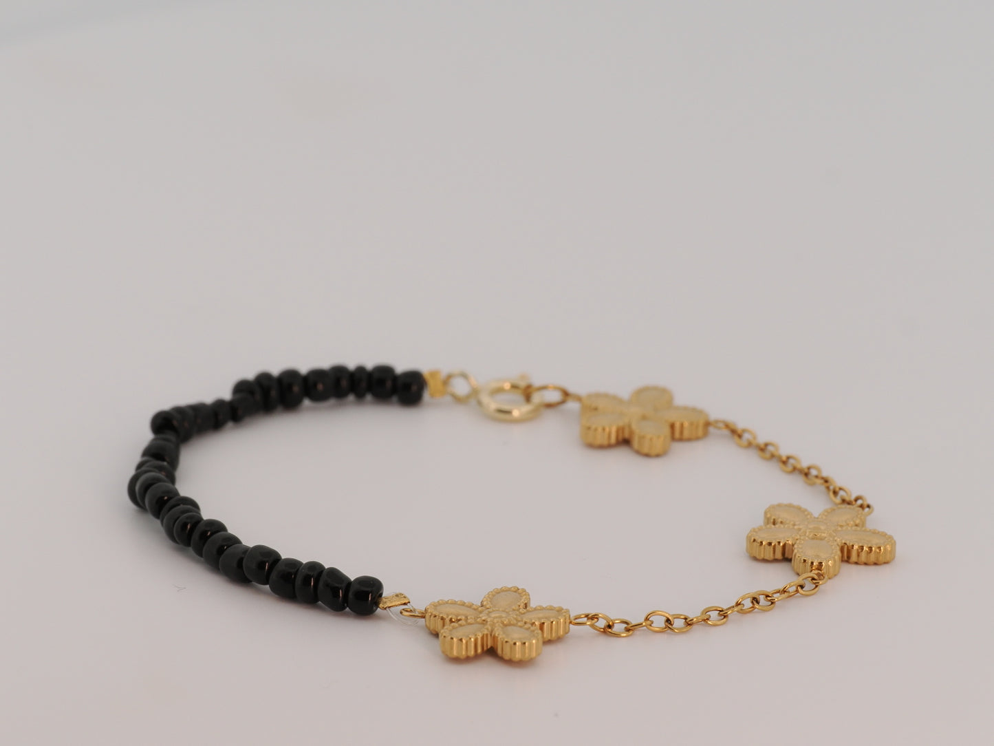 Bracelet with black beads and gold crosses on a light gray background