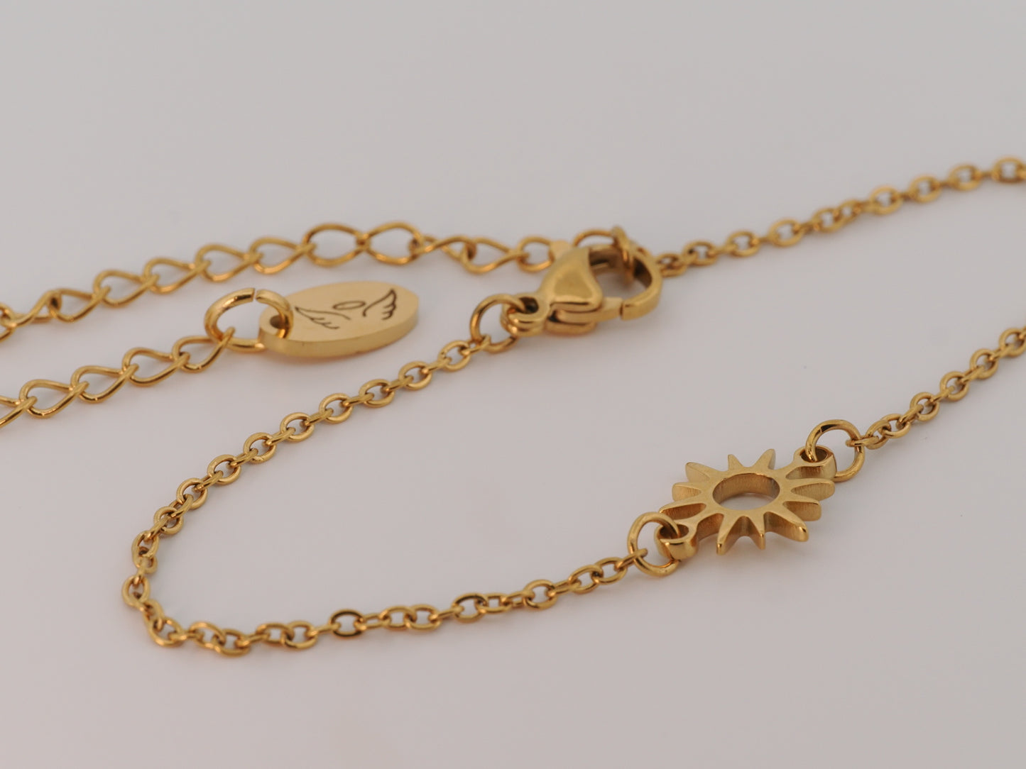 Gold chain bracelet with a sun-shaped clasp on a light gray background