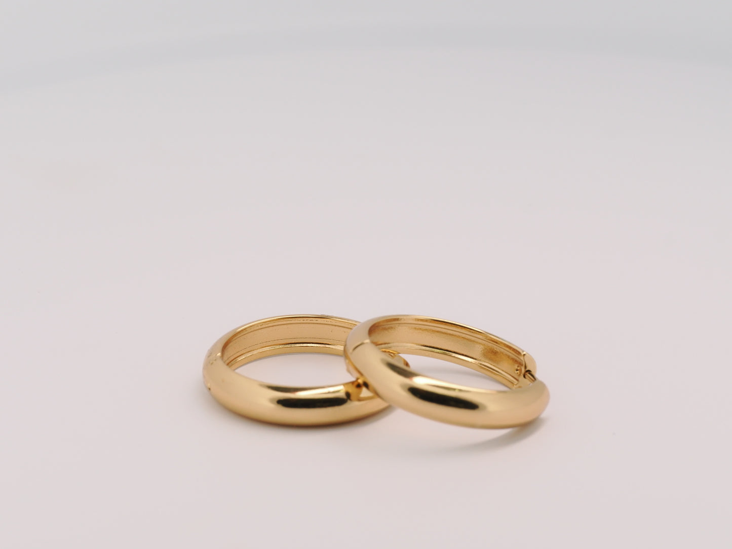 Two gold rings on a light gray background