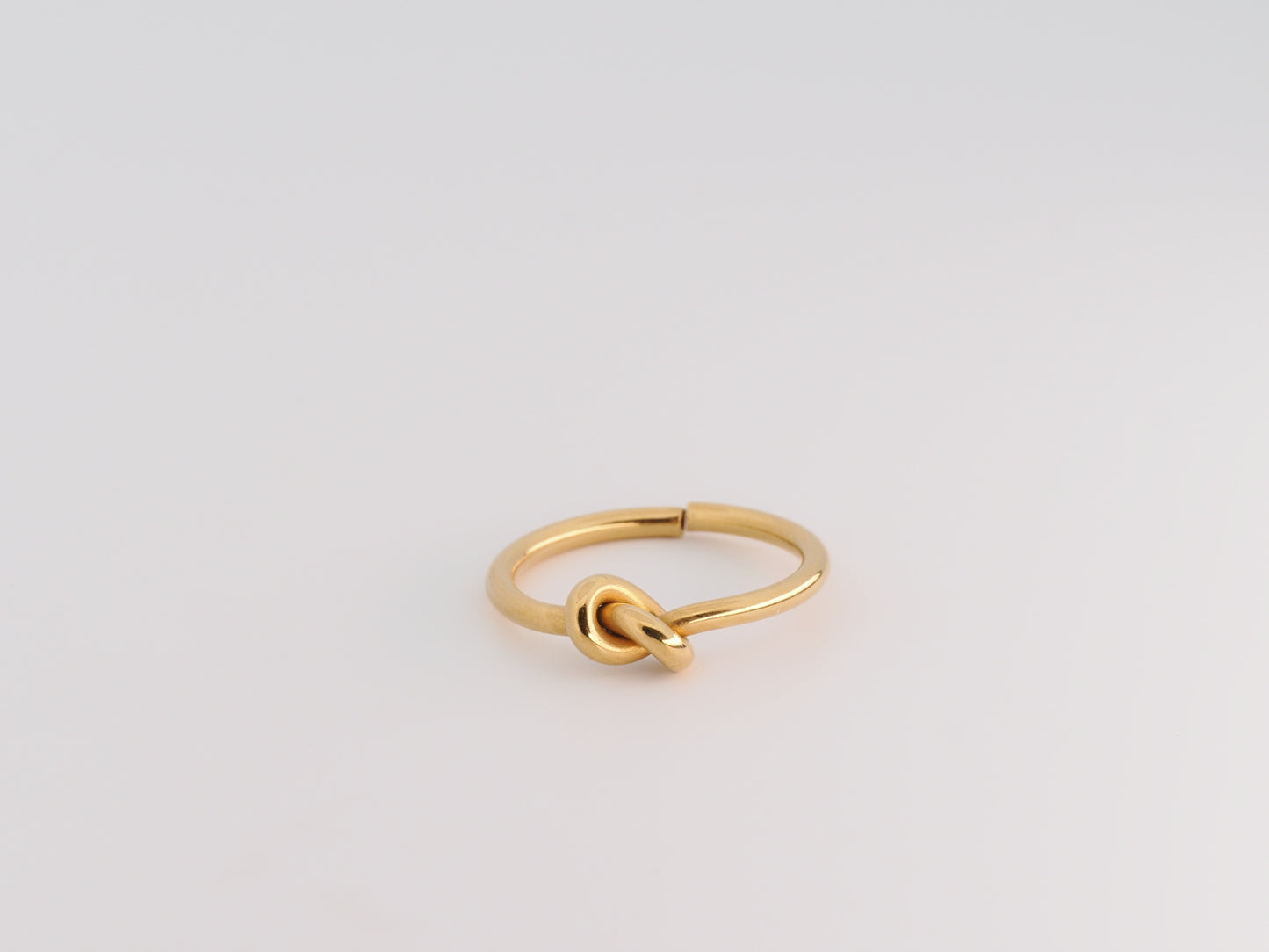Gold knot ring on a light gray background