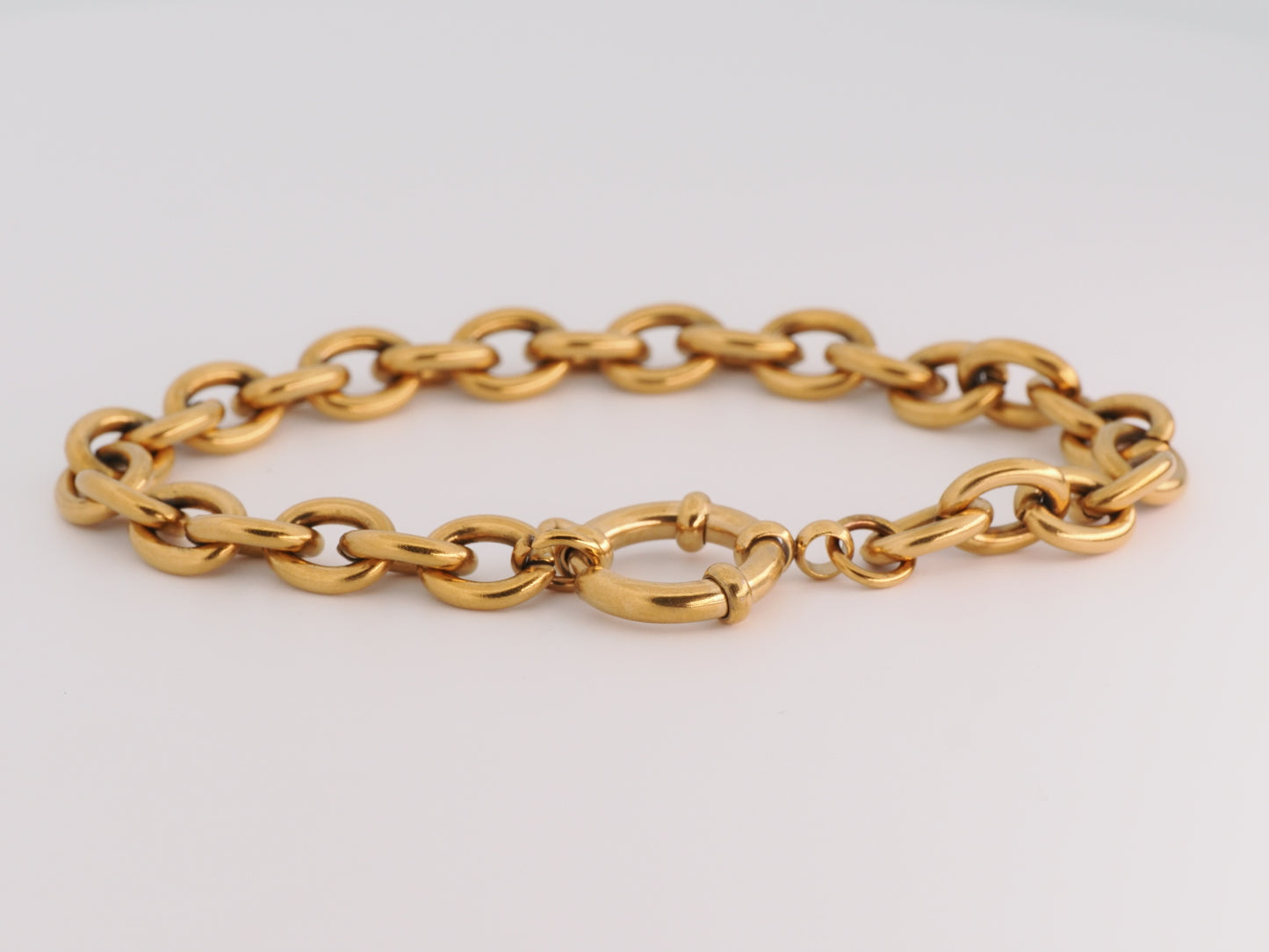 Gold chain bracelet on a light gray background