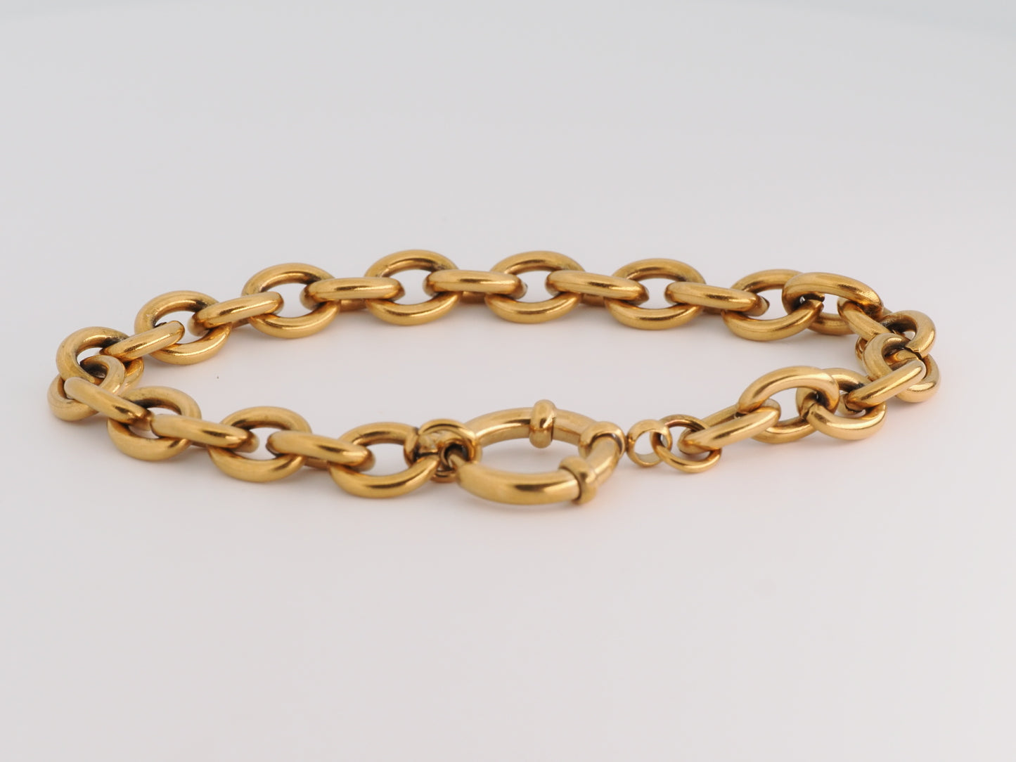 Gold chain bracelet on a light gray background