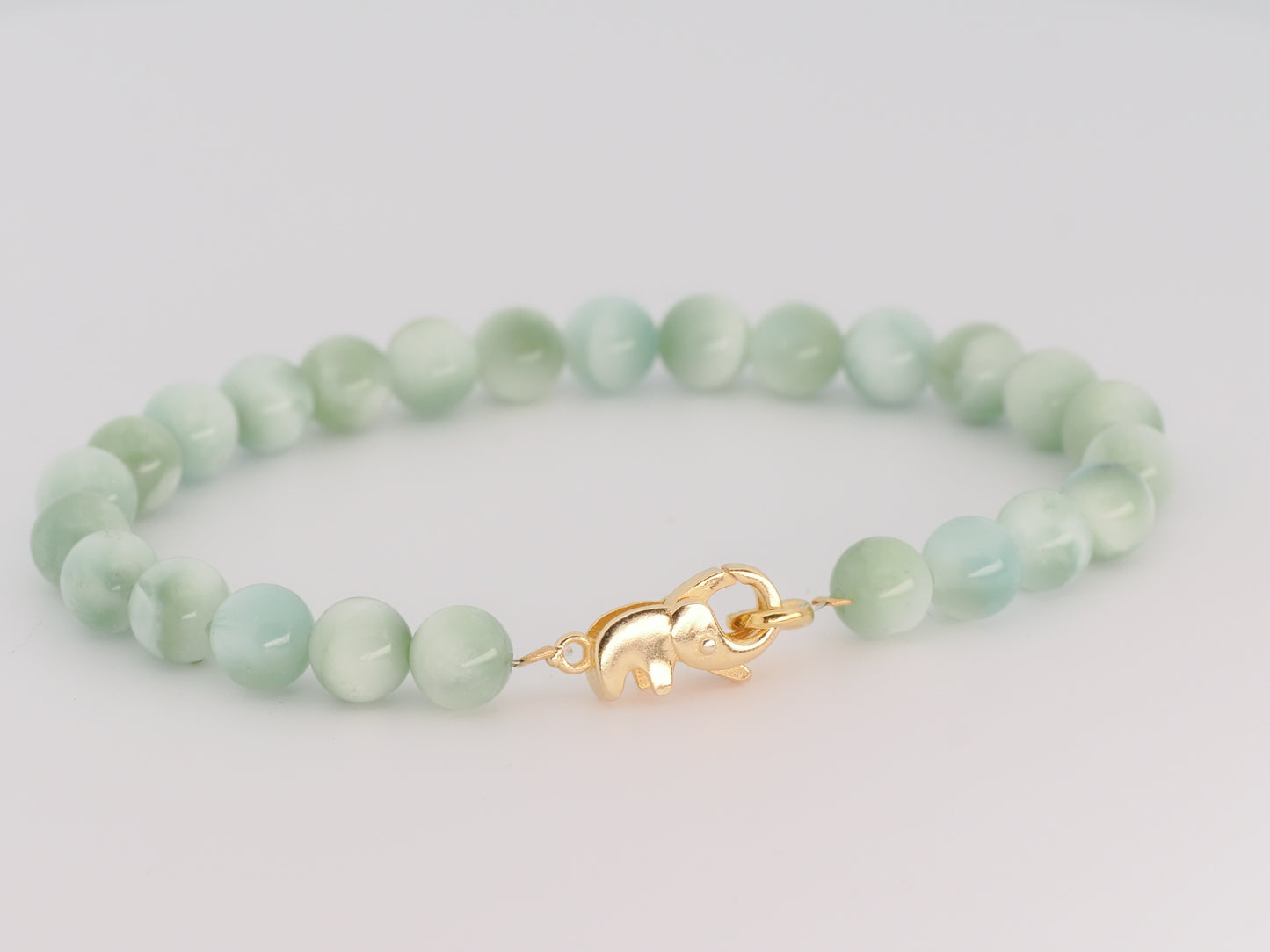 Green beaded bracelet with a gold clasp on a light gray background