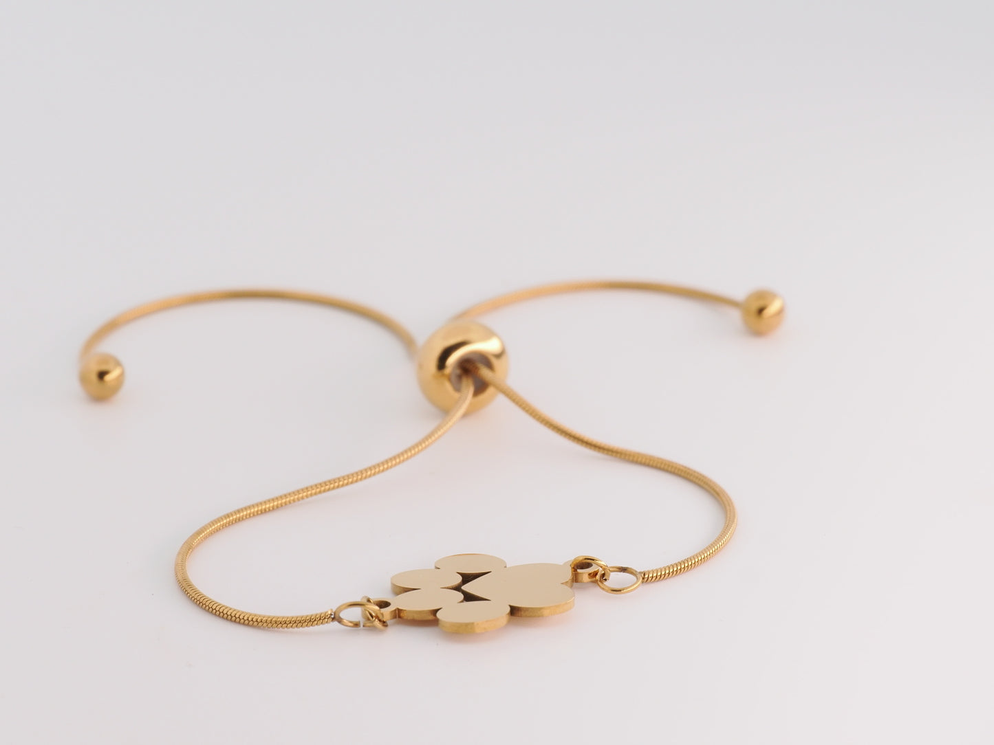 Gold bracelet with a paw print charm on a light gray background