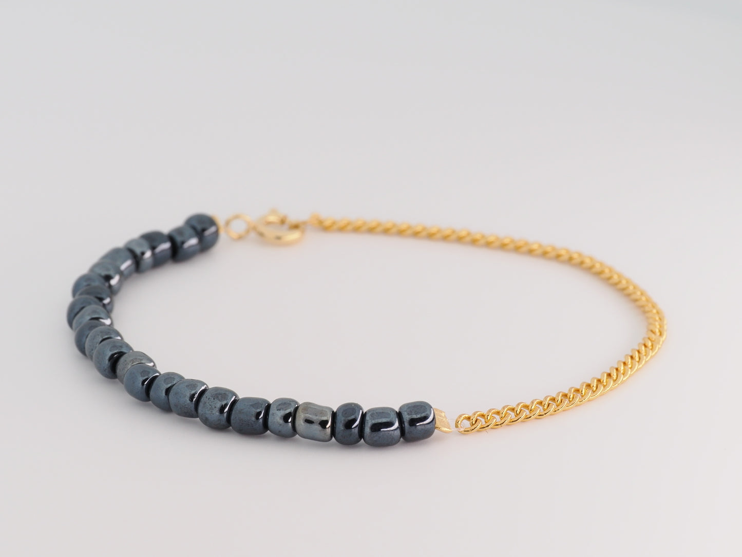 Bracelet with blue beads and gold chain on a light gray background