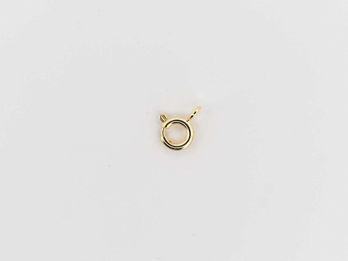 Gold necklace clasp on a light gray background