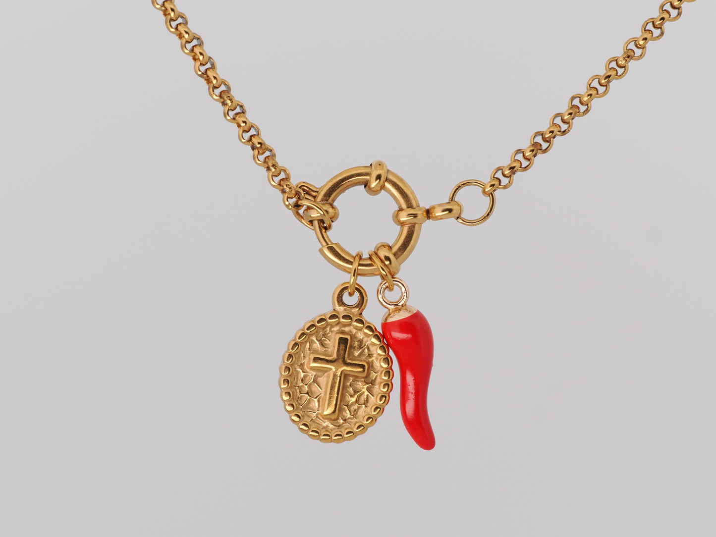 Gold necklace with a red chili pepper charm on a gray background