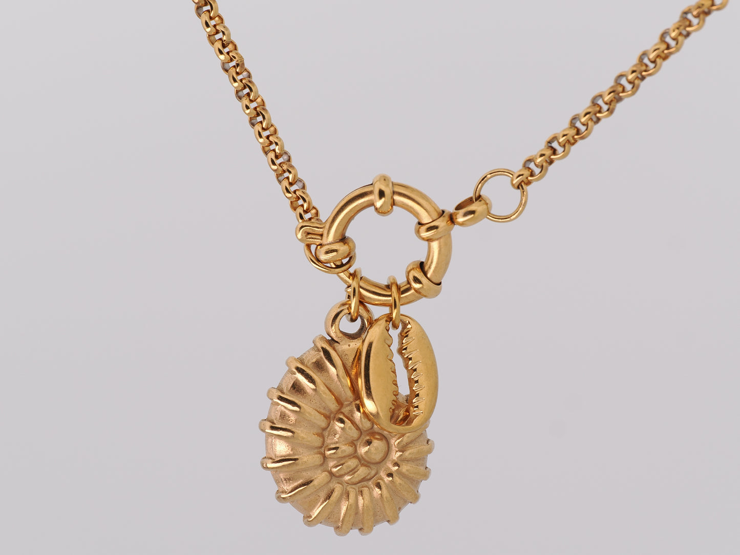 Gold necklace with a sunflower pendant on a light gray background