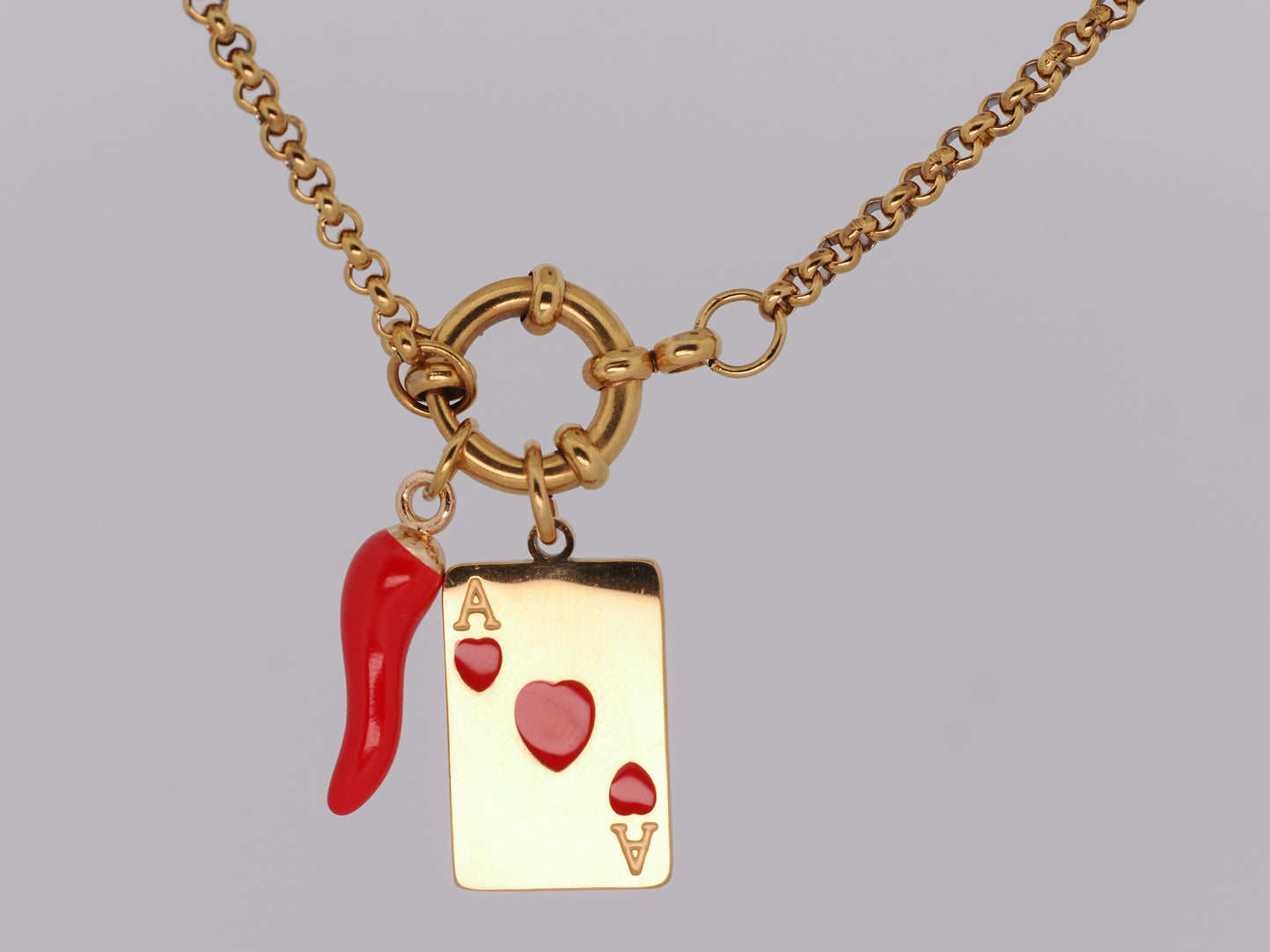 Gold necklace with a red and gold card suit charm on a gray background