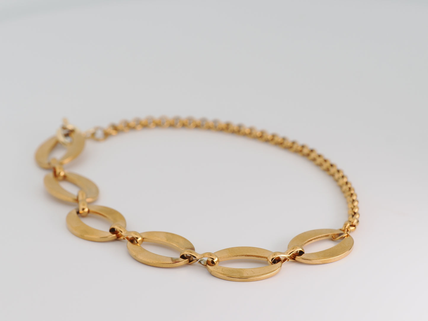 Gold bracelet on a light gray background