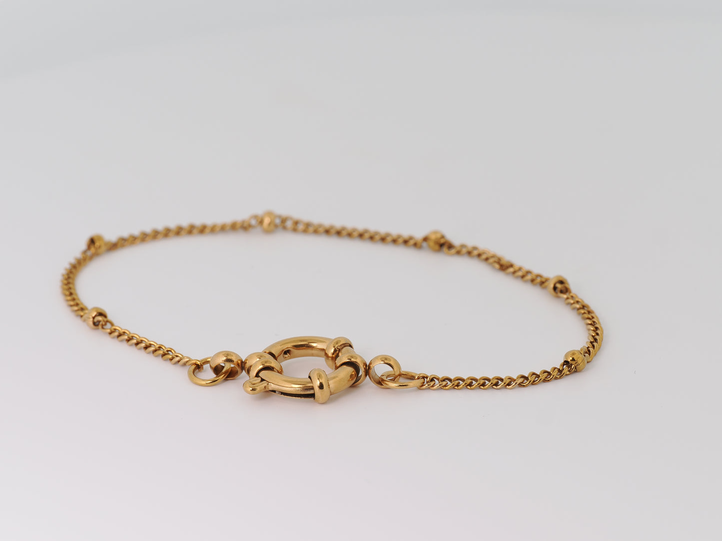 Gold bracelet on a light gray background
