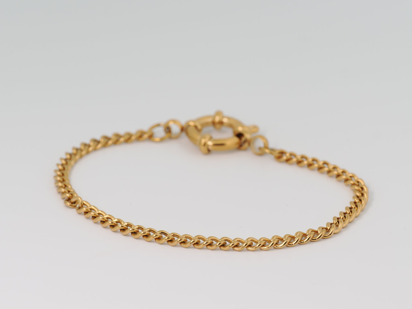Gold chain bracelet on a light gray background