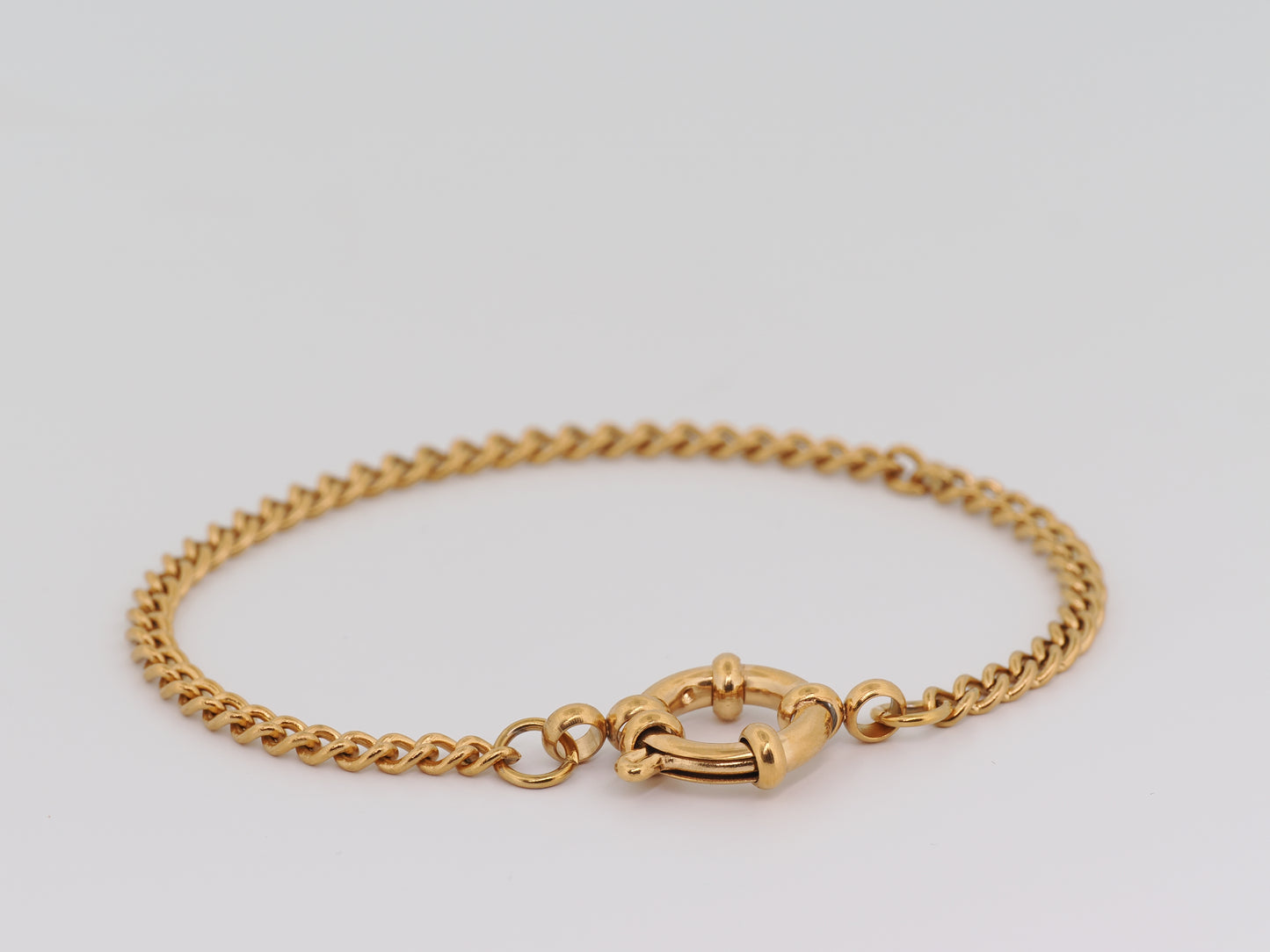 Gold chain bracelet on a light gray background