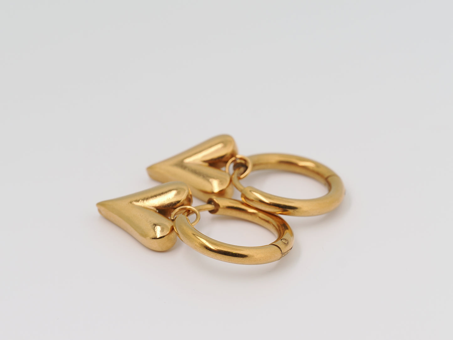 Gold keychain with heart and circular design on a light gray background