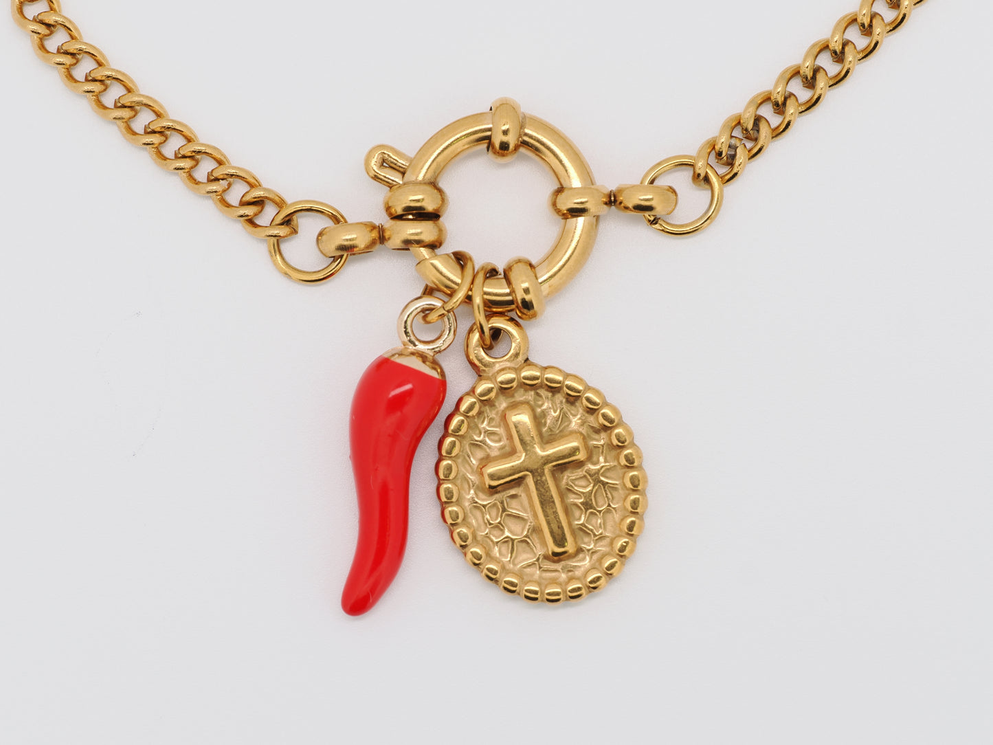 Gold necklace with a red chili pepper charm and a cross pendant on a white background