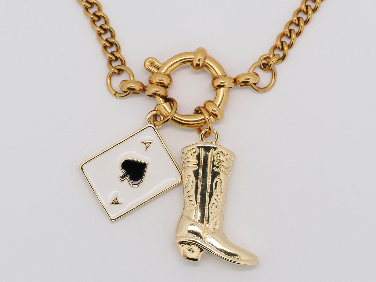 Gold necklace with a spade card and cowboy boot charm on a white background