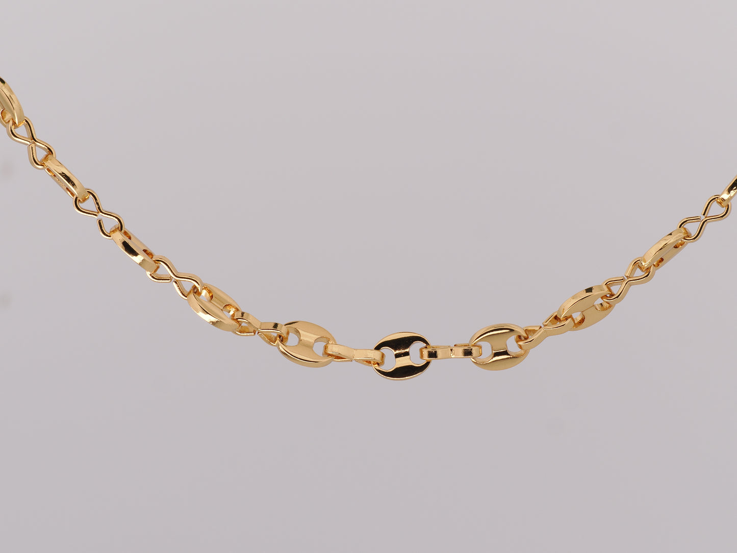 Gold chain necklace on a gray background