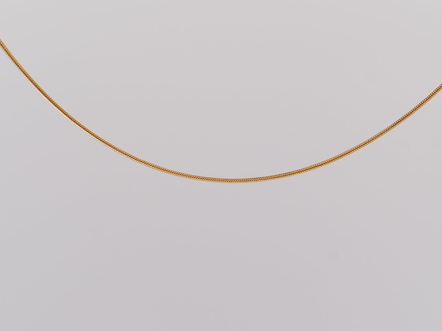 Gold chain on a light gray background