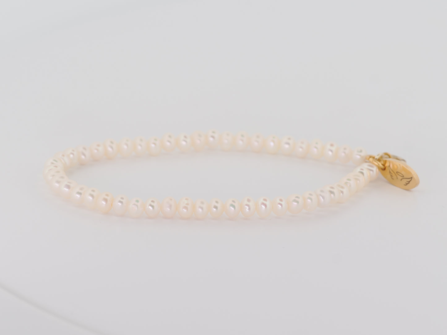 Pearl bracelet with a gold clasp on a light gray background