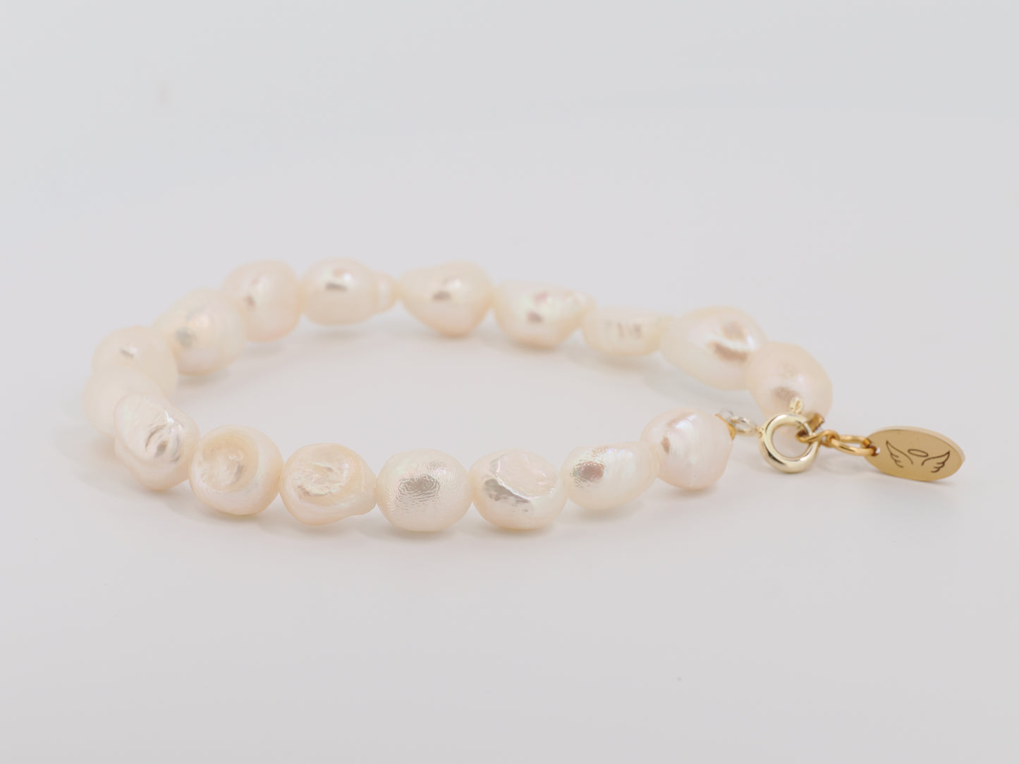 Pearl bracelet with a gold clasp on a light gray background