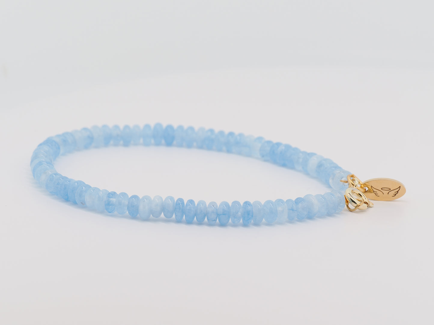 Blue beaded bracelet with a gold charm on a light gray background