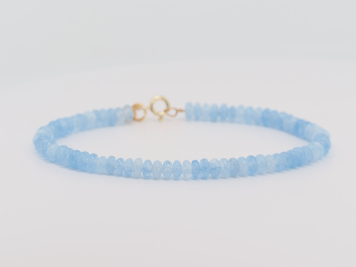Light blue beaded bracelet with a gold clasp on a light gray background