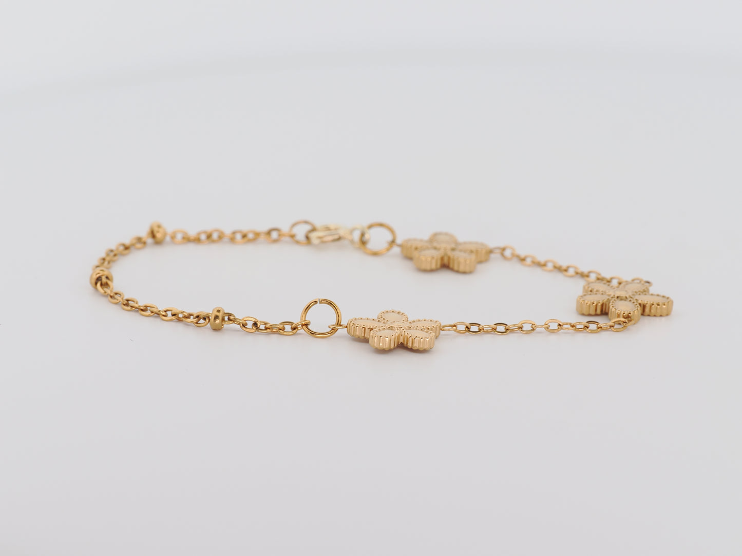 Gold bracelet with floral links on a light gray background