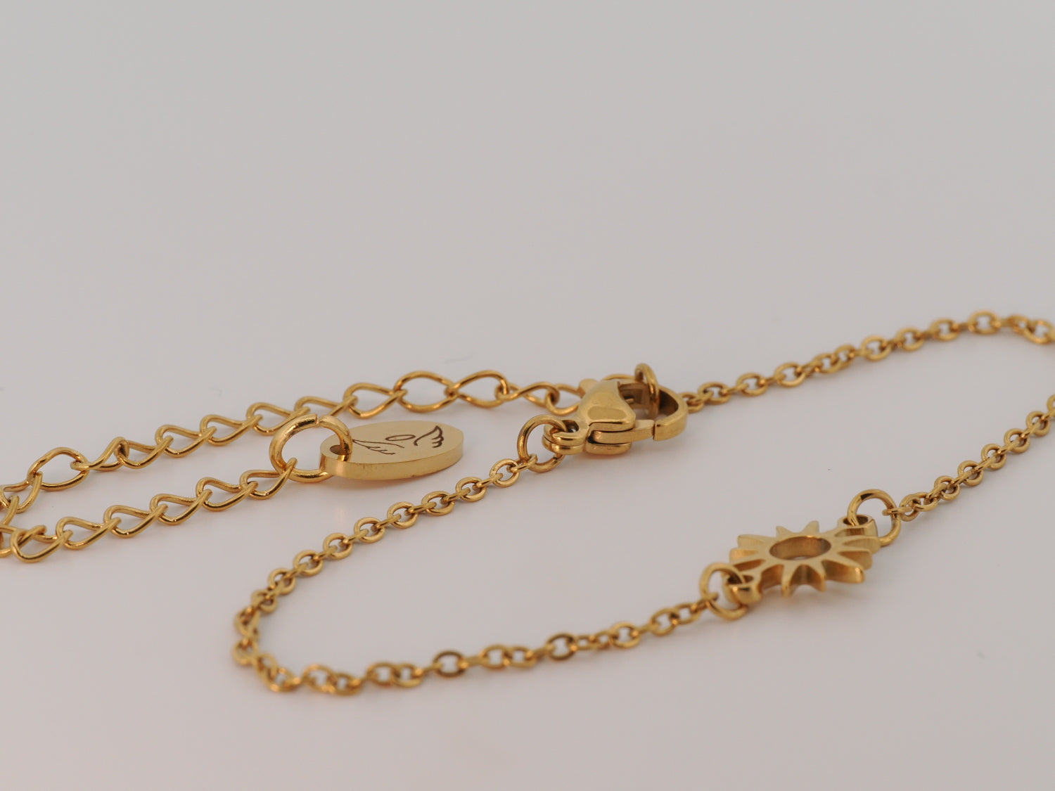 Gold bracelet with a sun design on a light gray background