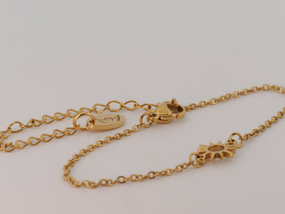 Gold bracelet with a sun design on a light gray background