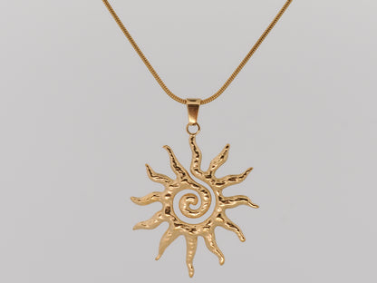Gold sun-shaped pendant on a chain against a gray background