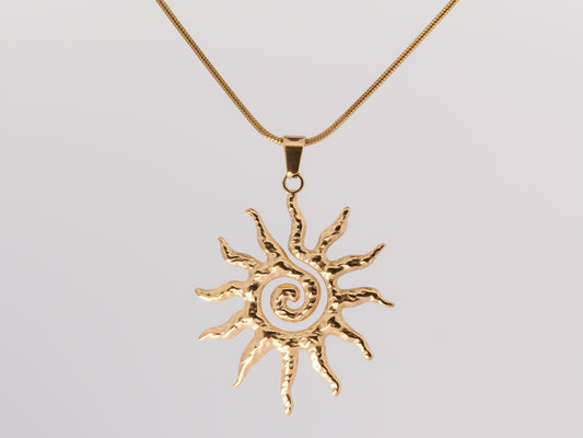 Gold sun-shaped pendant on a chain against a light gray background