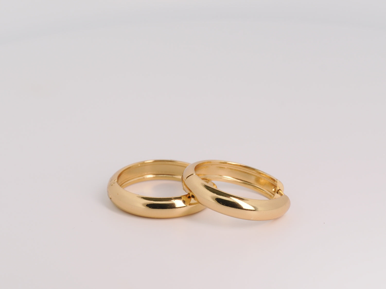 Two gold rings on a light gray background