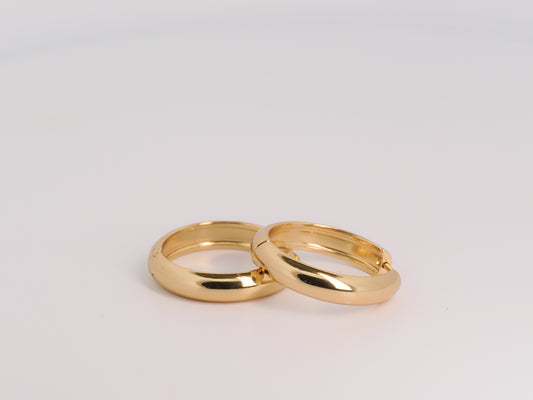 Two gold rings on a light gray background