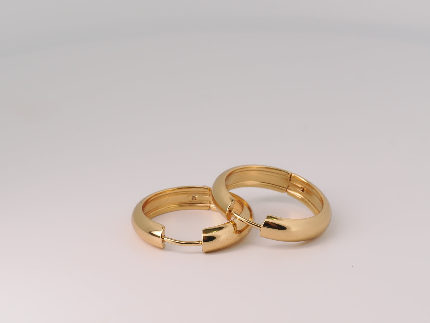 Pair of gold hoop earrings on a light gray background