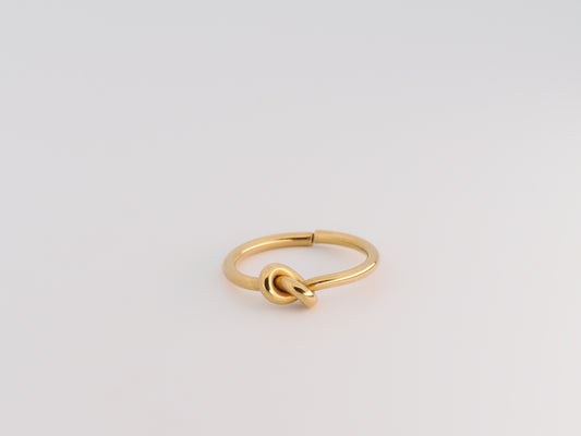 Gold knot ring on a light gray background