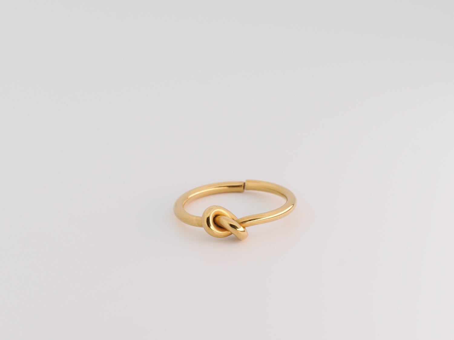 Gold knot ring on a light gray background