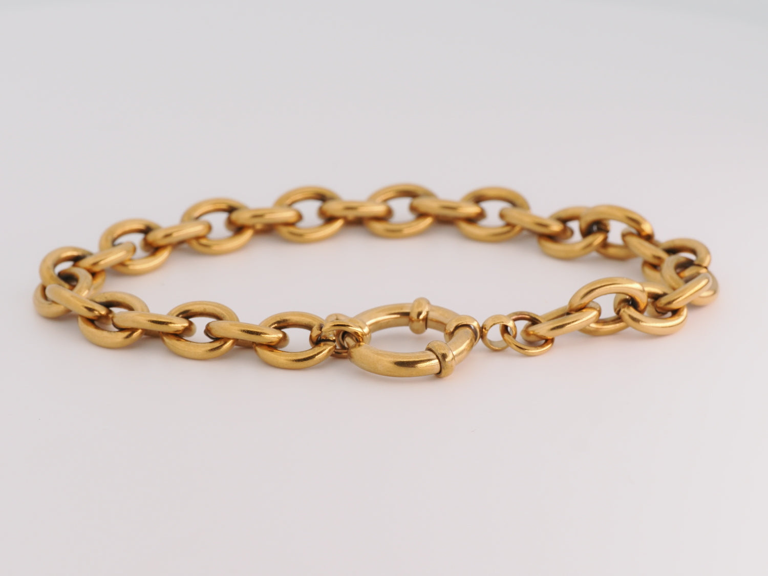 Gold chain bracelet on a light gray background