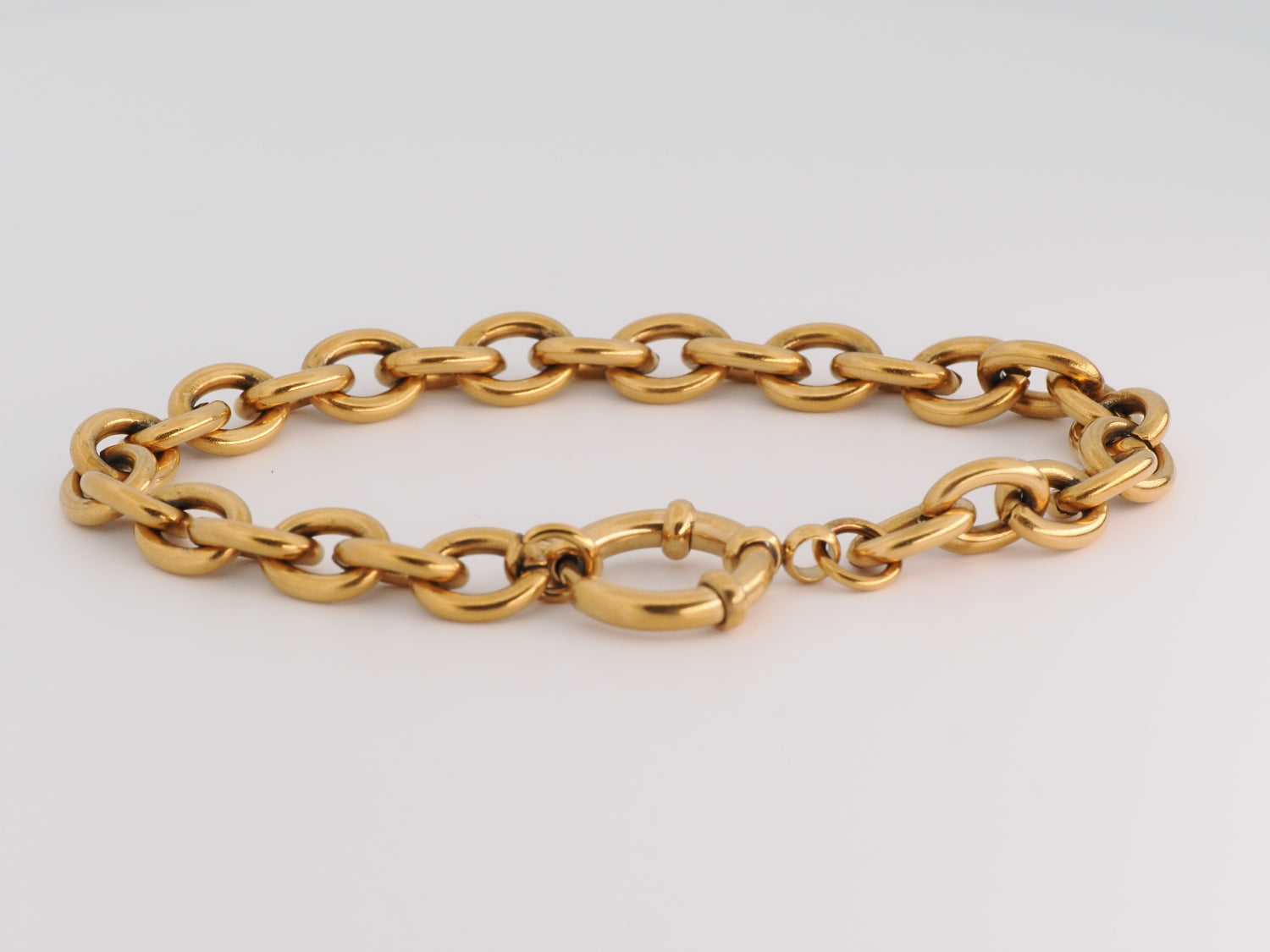 Gold chain bracelet on a light gray background