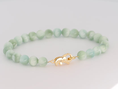 Green beaded bracelet with a gold clasp on a light gray background