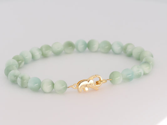 Green beaded bracelet with a gold clasp on a light gray background