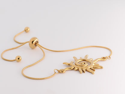 Gold bracelet with sun-shaped clasp on a light gray background