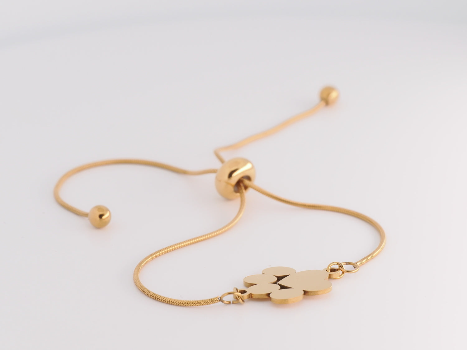 Gold bracelet with a paw print charm on a light gray background