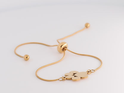 Gold bracelet with a paw print charm on a light gray background