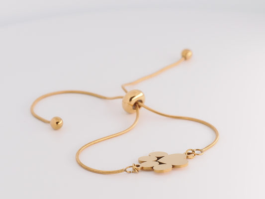 Gold bracelet with a paw print charm on a light gray background