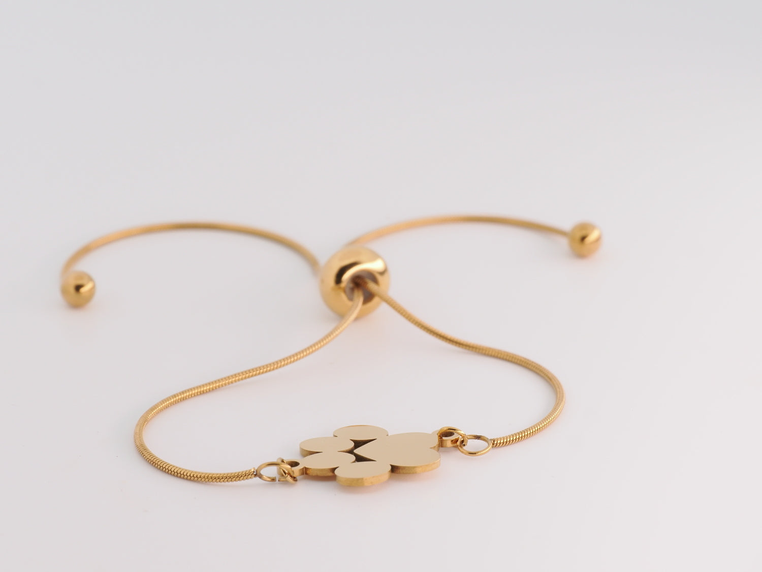 Gold bracelet with a paw print charm on a light gray background
