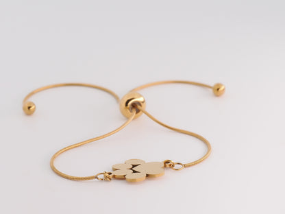 Gold bracelet with a paw print charm on a light gray background