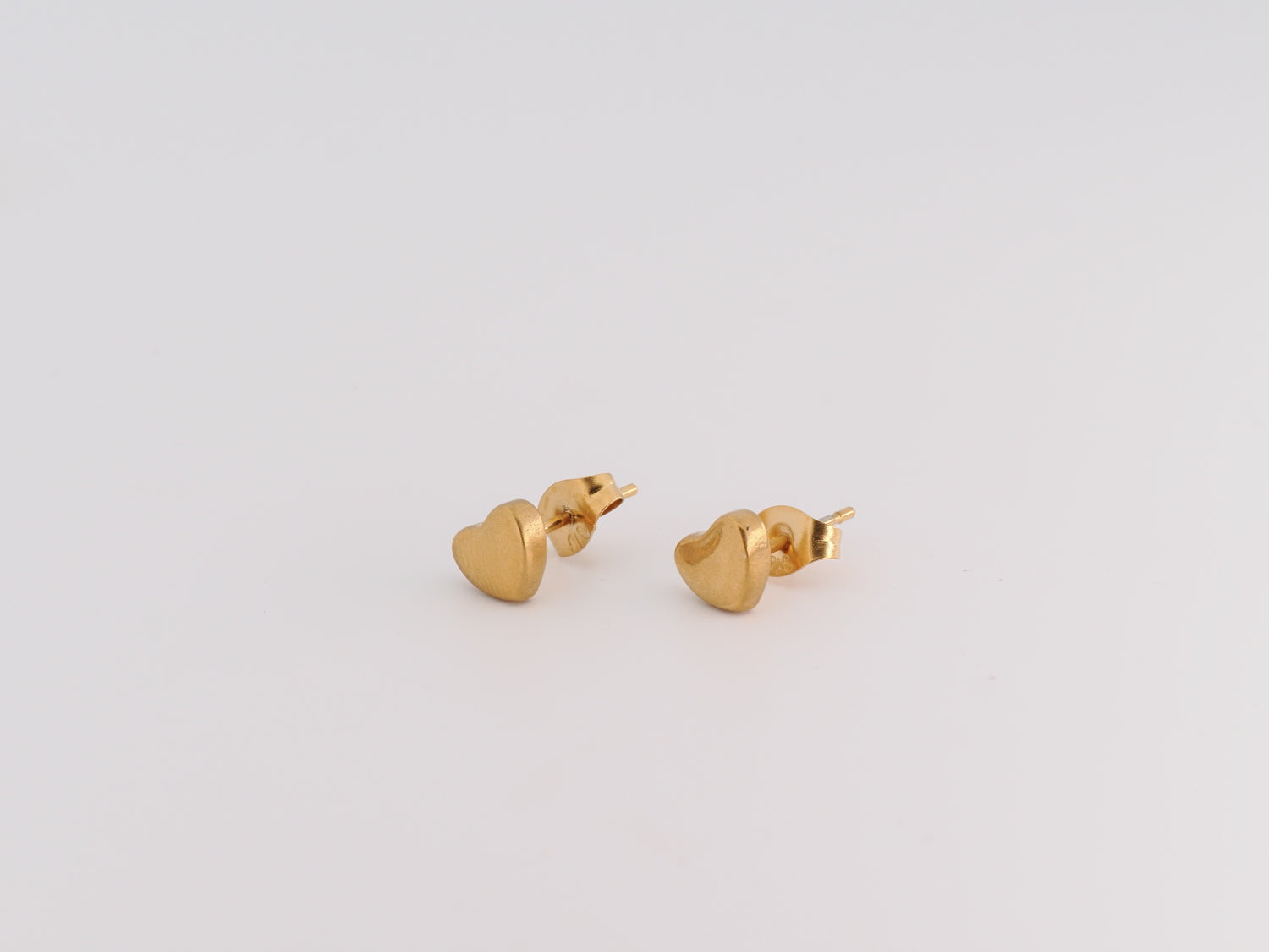 Gold heart-shaped earrings on a light gray background