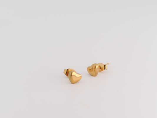 Gold heart-shaped earrings on a light gray background