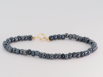 Gray beaded necklace with a gold clasp on a light gray background