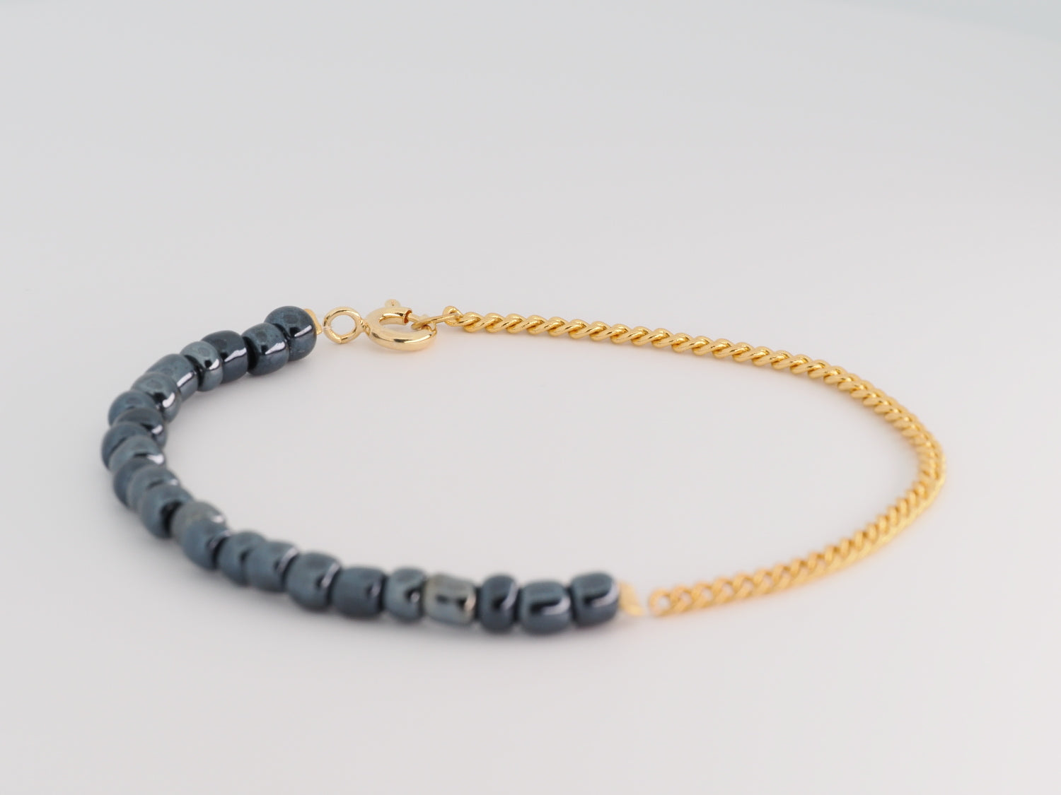 Bracelet with blue beads and gold chain on a light gray background